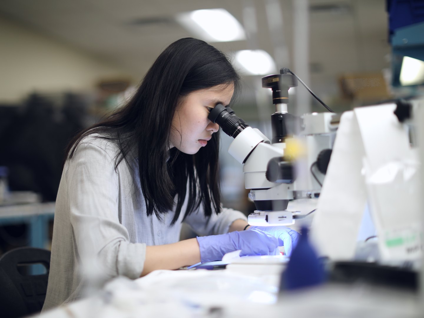 Quality engineer inspecting a component through a stereo microscope