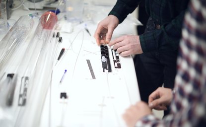 Hands assembling catheter components on a bench fixture