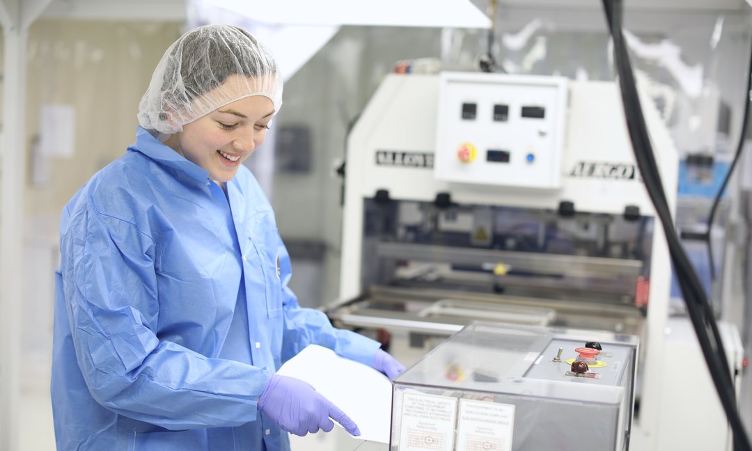 Gowned operator running a machine in a cleanroom Gowned operator running a machine in a cleanroom