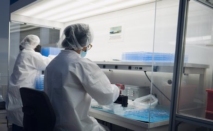 Gowned operators working at hooded cleanroom stations