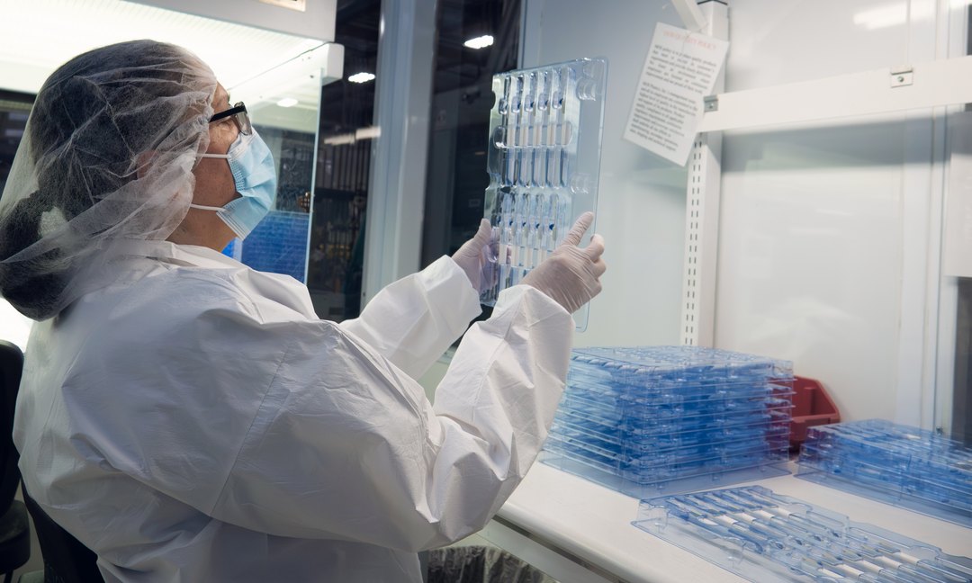 Cleanroom operator in a mask inspecting a molded tray