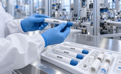 Cleanroom technician inspecting an autoinjector pen beside a tray of drug delivery devices and components.