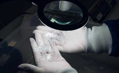 Clear injection-molded parts inspected under a magnifier